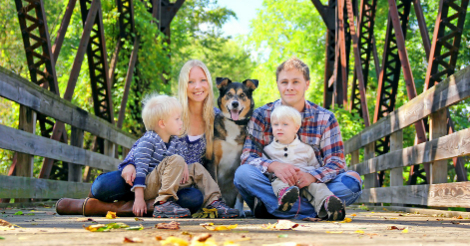 A family of four, in which there are two children, with a pet dog. one of the children is looking at the dog.
Tips for taking care of a pet dog include introducing your family to your pet dog for better bonds and to prevent your dog from attacking your family.